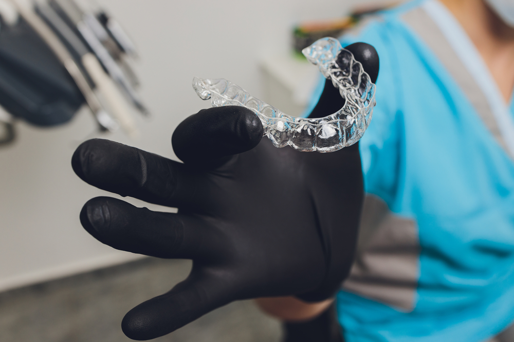 Close Up,of,a,woman's,hand,putting,transparent,aligner,in,teeth.
