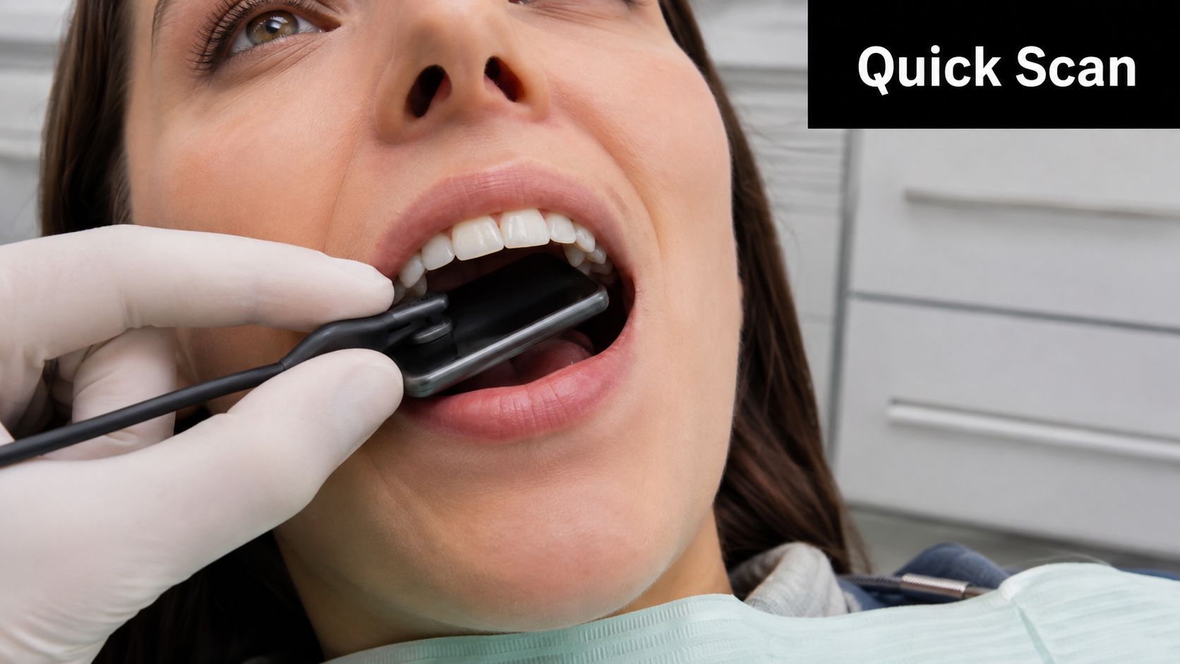 A dentist wearing gloves places a digital dental radiography sensor inside a patient's mouth for imaging.
