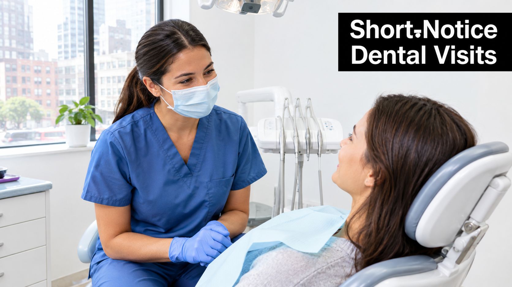 A friendly dental assistant wearing a mask and scrubs talking to a female patient in a chair.