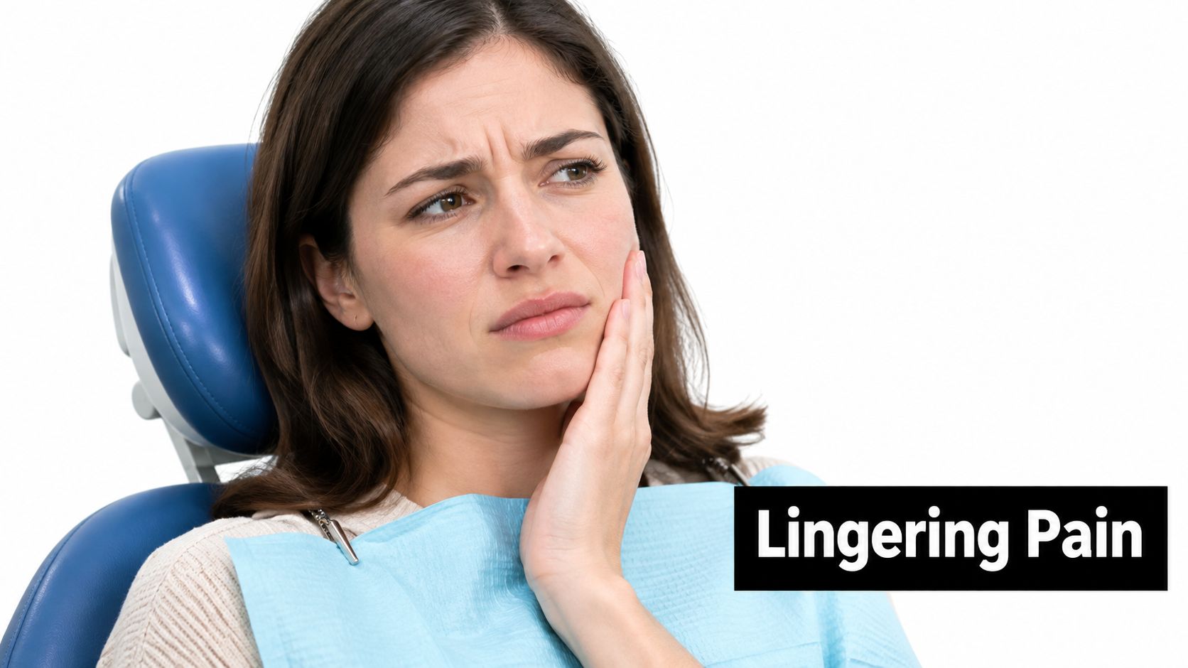 A woman sitting in a dental chair looking distressed while holding her jaw due to lingering pain.